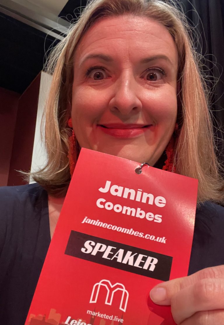 Janine Coombes holding up a MarketEd Live 2023 Speaker lanyard